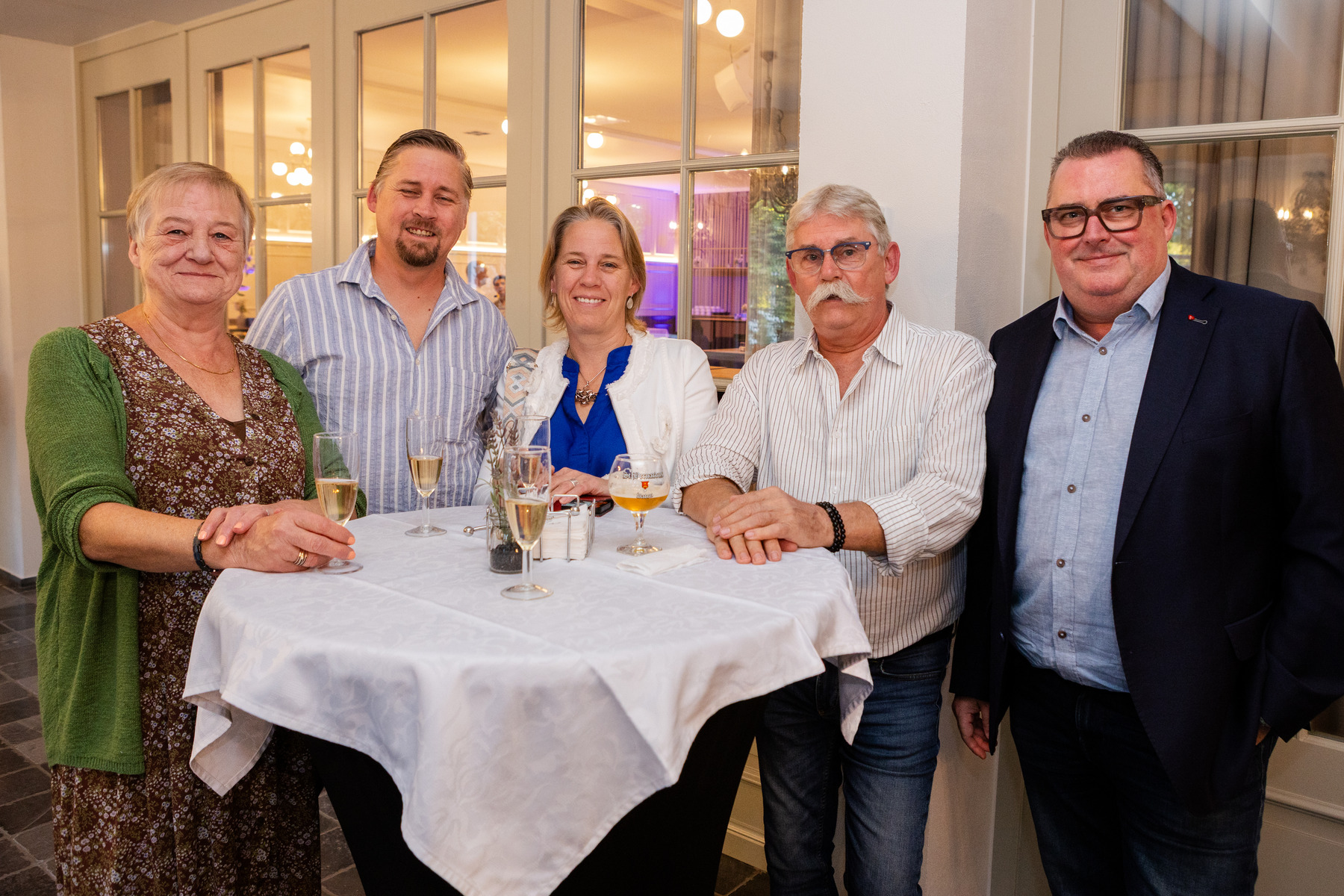 Gasten samen rond een statafel tijdens het jubileumfeest.